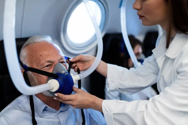 Female Doctor Adjusting Oxygen Mask Senior Patient Hyperbaric Chamber Clinic — Stockfoto