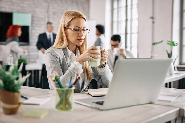 Beautiful Pensive Businesswoman Reading Something Laptop Drinking Tea While Sitting — Stock Fotó