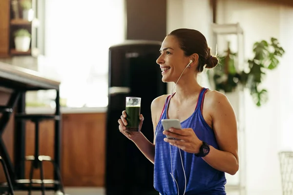 Happy Athletic Woman Listening Music Earphones Drinking Detox Smoothie Home —  Fotos de Stock