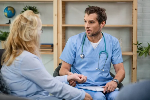 Male Doctor Talking Female Patient While Taking Her Pulse Home — Stockfoto