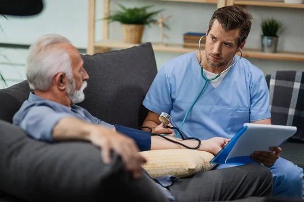 Worried Doctor Communicating Senior Patient While Measuring His Blood Pressure — Fotografia de Stock