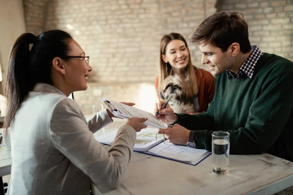 Young Happy Couple Signing Document While Having Meeting Real Estate — стоковое фото