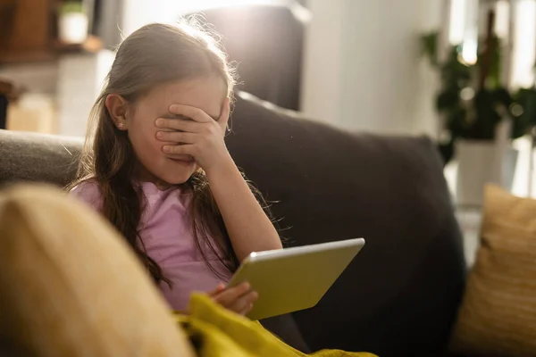 Scared Little Girl Covering Her Eyes While Surfing Internet Touchpad — Stockfoto