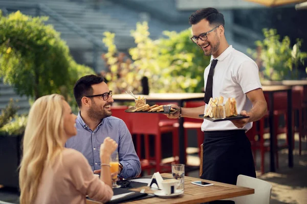 Young Smiling Waiter Serving Couple Bringing Them Food Lunch Time — Foto de Stock