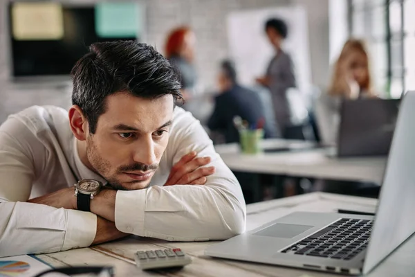 Young Businessman Thinking Something While Leaning His Desk Using Computer — Foto de Stock