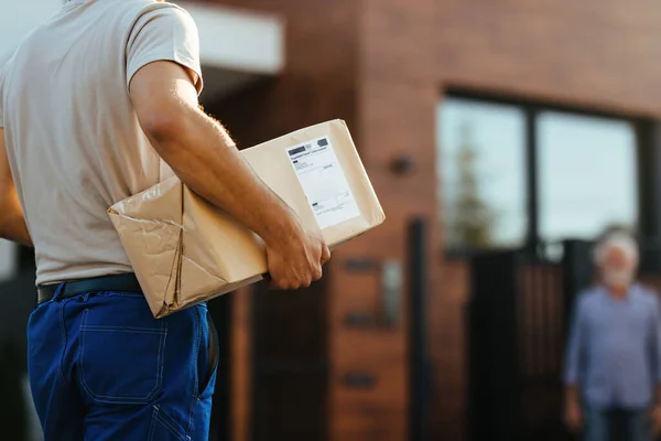 Unrecognizable Courier Carrying Package While Making Home Delivery His Customer — Stockfoto