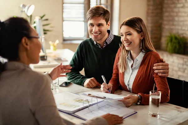 Young Happy Couple Signing Contract While Being Meeting Insurance Agent — стоковое фото