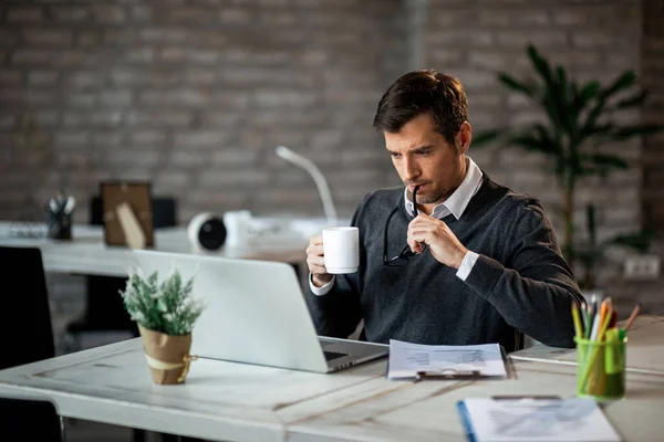 Mid Adult Businessman Using Computer While Working Reports Drinking Coffee — Stockfoto