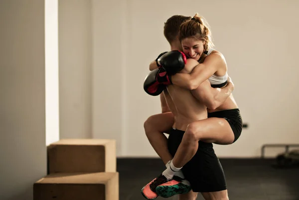 Happy female boxer embracing her personal instructor after sports training in a gym. Copy space.
