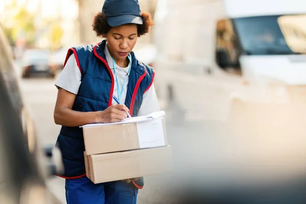 Black Female Courier Writing Address While Delivering Packages City — Stock Fotó