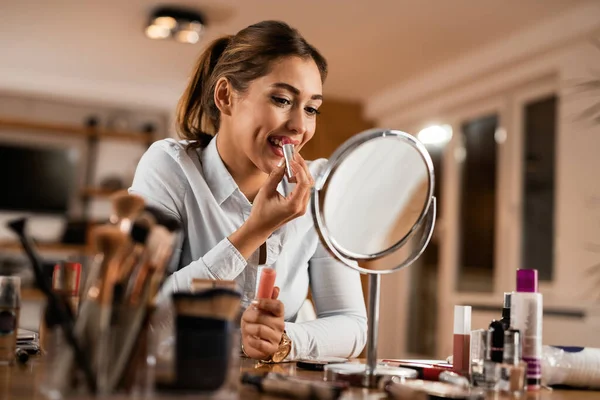 Νεαρή Χαμογελαστή Γυναίκα Που Βάζει Κραγιόν Ενώ Κοιτιέται Καθρέφτη Μακιγιάζ — Φωτογραφία Αρχείου