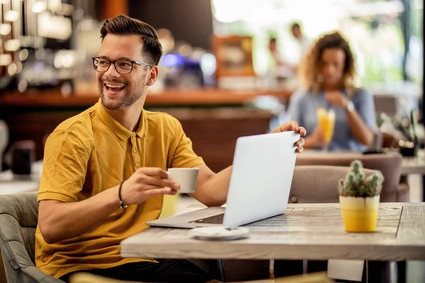 Νεαρός Ευτυχισμένος Άνθρωπος Απολαμβάνοντας Φλιτζάνι Καφέ Ενώ Χρησιμοποιώντας Τον Υπολογιστή — Φωτογραφία Αρχείου