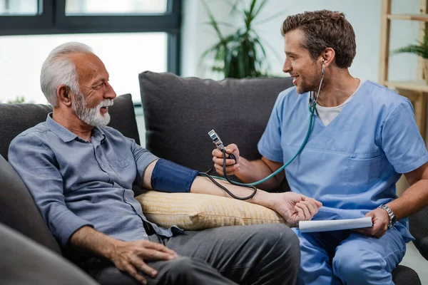 Happy Doctor Visiting Senior Patient Home Measuring His Blood Pressure — Fotografia de Stock