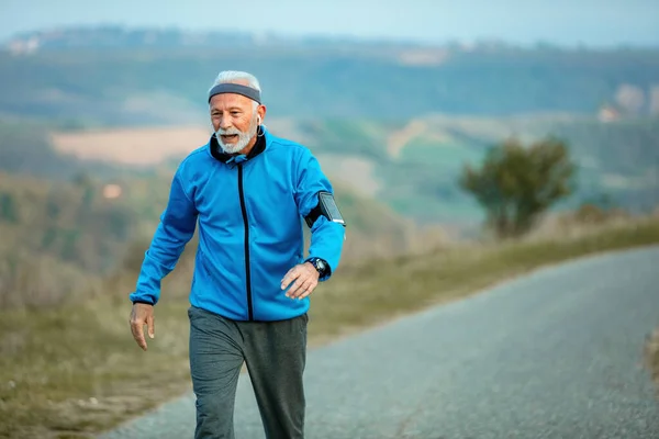 Active senior athlete making an effort while racewalking on the road in nature. Copy space.