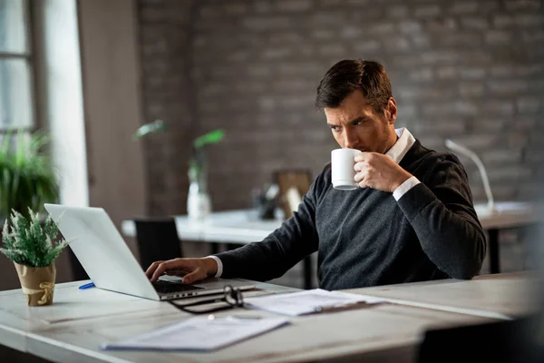 Άντρας Επιχειρηματίας Σερφάρει Στο Διαδίκτυο Στο Laptop Και Πίνοντας Καφέ — Φωτογραφία Αρχείου
