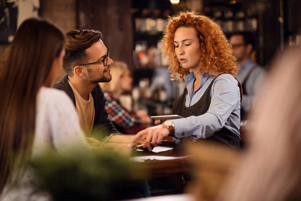 Young Waitress Talking Guests Pointing Menu While Taking Orders Them — Stockfoto