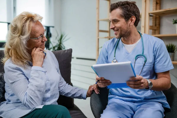 Happy Doctor Communicating Senior Woman Medical Documents While Being Home — Foto de Stock