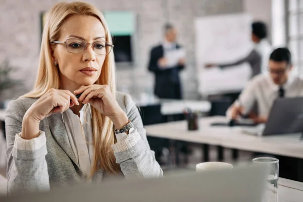 Serious Businesswoman Sitting Her Desk Office Thinking Something People Background — Foto de Stock