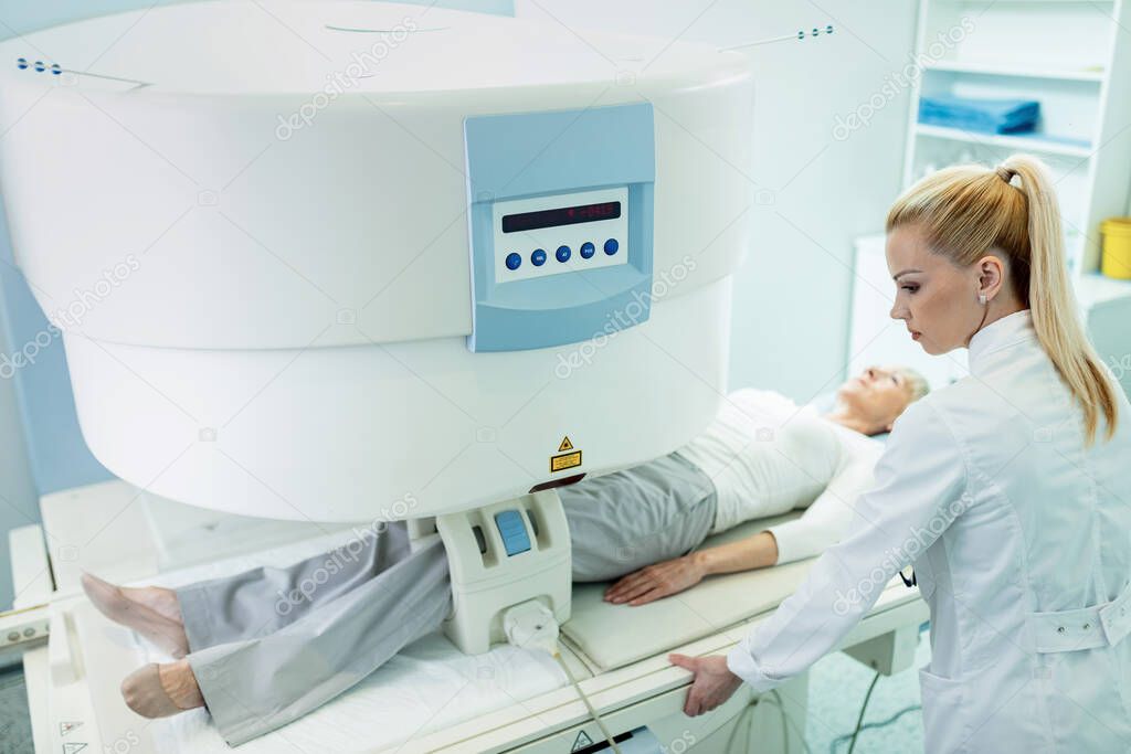 Female radiologist and a patient during knee MRI scan procedure in the hospital. 