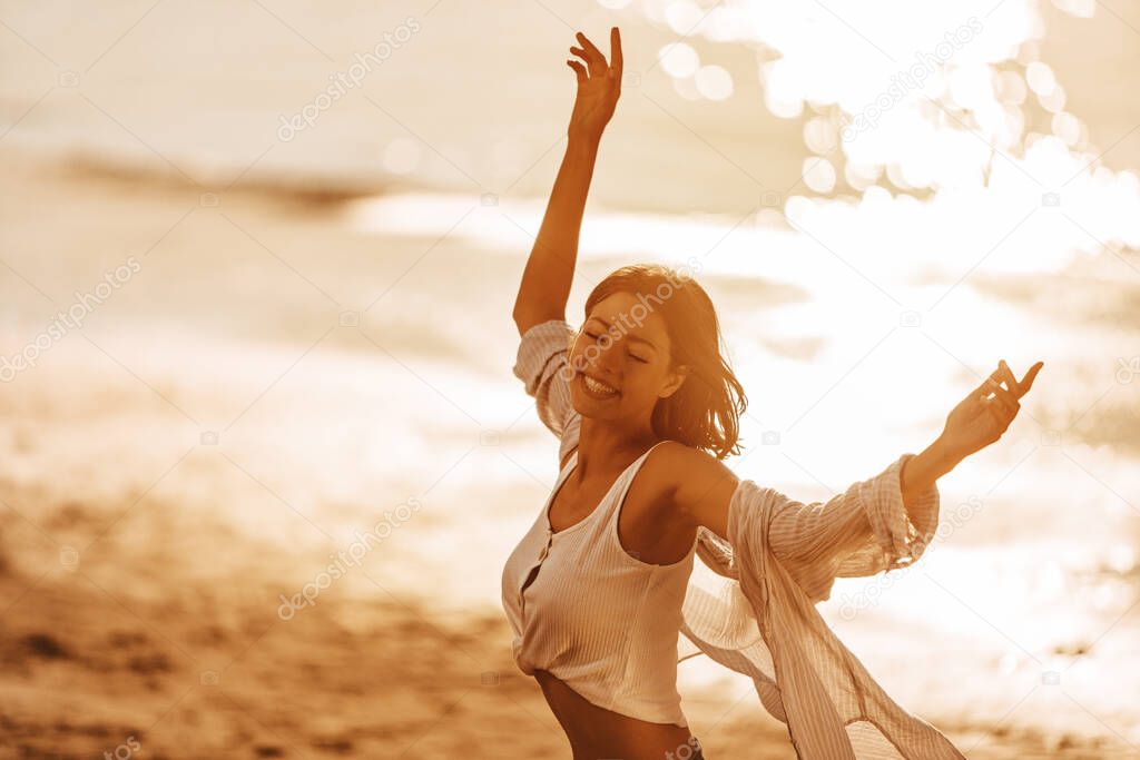 Carefree woman with arms outstretched having fun at summer sunset. 
