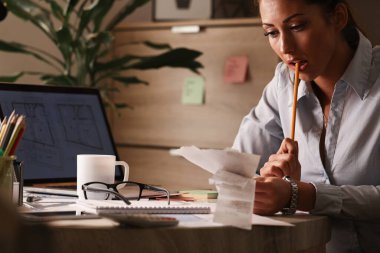 Pensive businesswoman working on her finances and calculating tax bills in the office. 