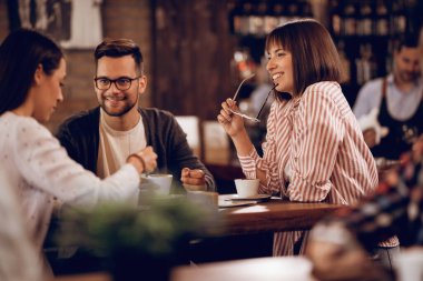 Small group of friends drinking coffee and communicating while sitting in a cafe. 