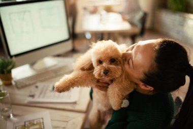 Asyalı serbest çalışan ofiste köpeğine sarılırken eğleniyor.. 