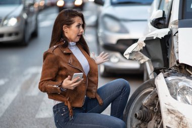 Petrified woman feeling shocked while looking at her damaged car after the accident. 