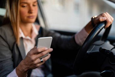 Close-up of businesswoman text messaging while driving a car to work. 