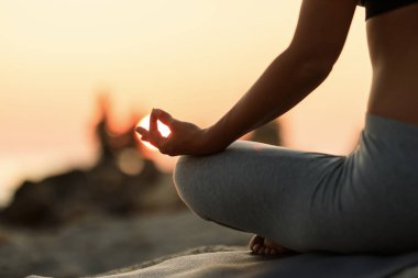 Close-up of woman practicing Yoga at sunset.
