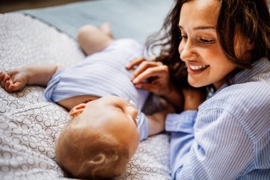Smiling mother looking with affection her sleeping baby at home. 