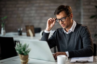 Male entrepreneur working on laptop while being in the office. 