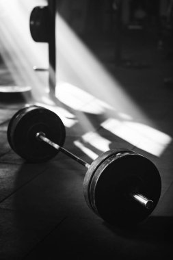 Black and white photo of a barbell in a gym. 