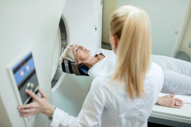 High angle view of mature woman and radiologist during MRI scan examination at clinic. 