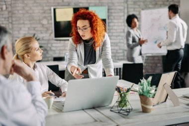 Business people cooperating while working together in modern office. There are people in the background. 