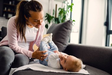 Young mother enjoying in time with her baby boy while doing infant development exercises at home. 