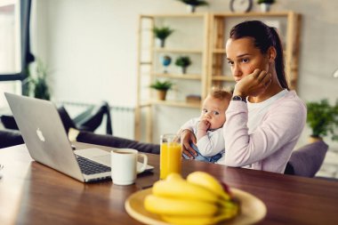 Young woman with baby experiencing postpartum depression and contemplating at home. 