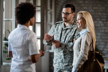 Military man is communicating with African American doctor while being with his wife at medical counselling. 