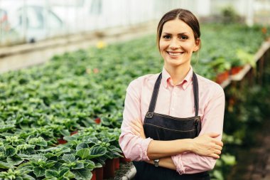 Confident greenhouse owner standing with arms crossed and smiling at camera. 