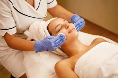 High angle view of young woman having facial treatment at beauty spa. 