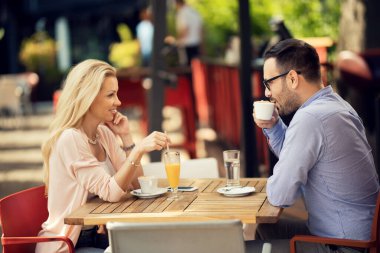 Smiling couple having a date in a cafe and communicating while drinking coffee. 