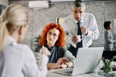 Small group of entrepreneurs communicating on business meeting in modern office.