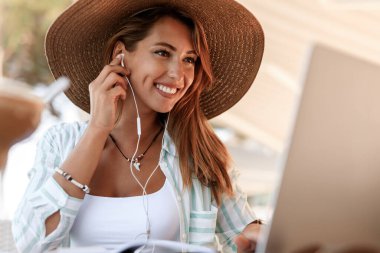 Happy woman surfing the net on laptop while relaxing in a cafe. 