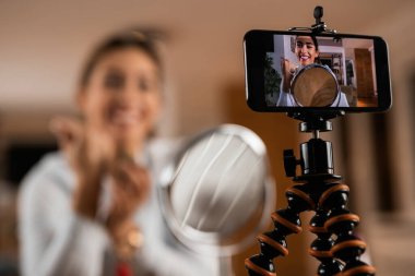 Close-up of happy vlogger filming make-up video tutorial at home. 
