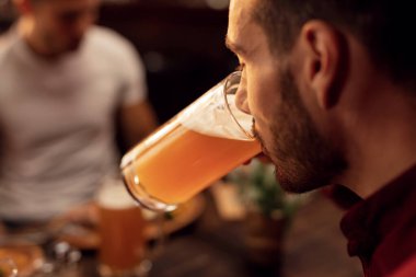 Close up of young man tasting lager beer in a pub. 