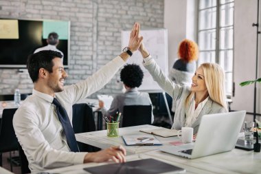Happy business people supporting each other and giving high five in the office.