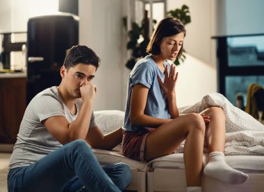 Young woman being angry at her boyfriend while having and argument with him in the bedroom. 