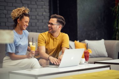Happy couple having fun while using computer and communicating in a cafe. 