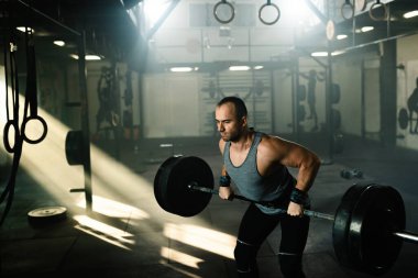 Bodybuilder exercising with barbell on weight training in a gym. 