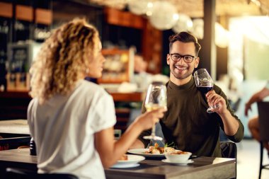 Happy couple enjoying in conversation while drinking wine and eating in a bar. 